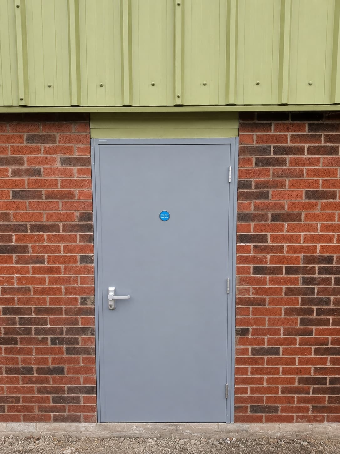 External fire door installed in brickwork and metal cladding wall as part of a commercial unit fit-out