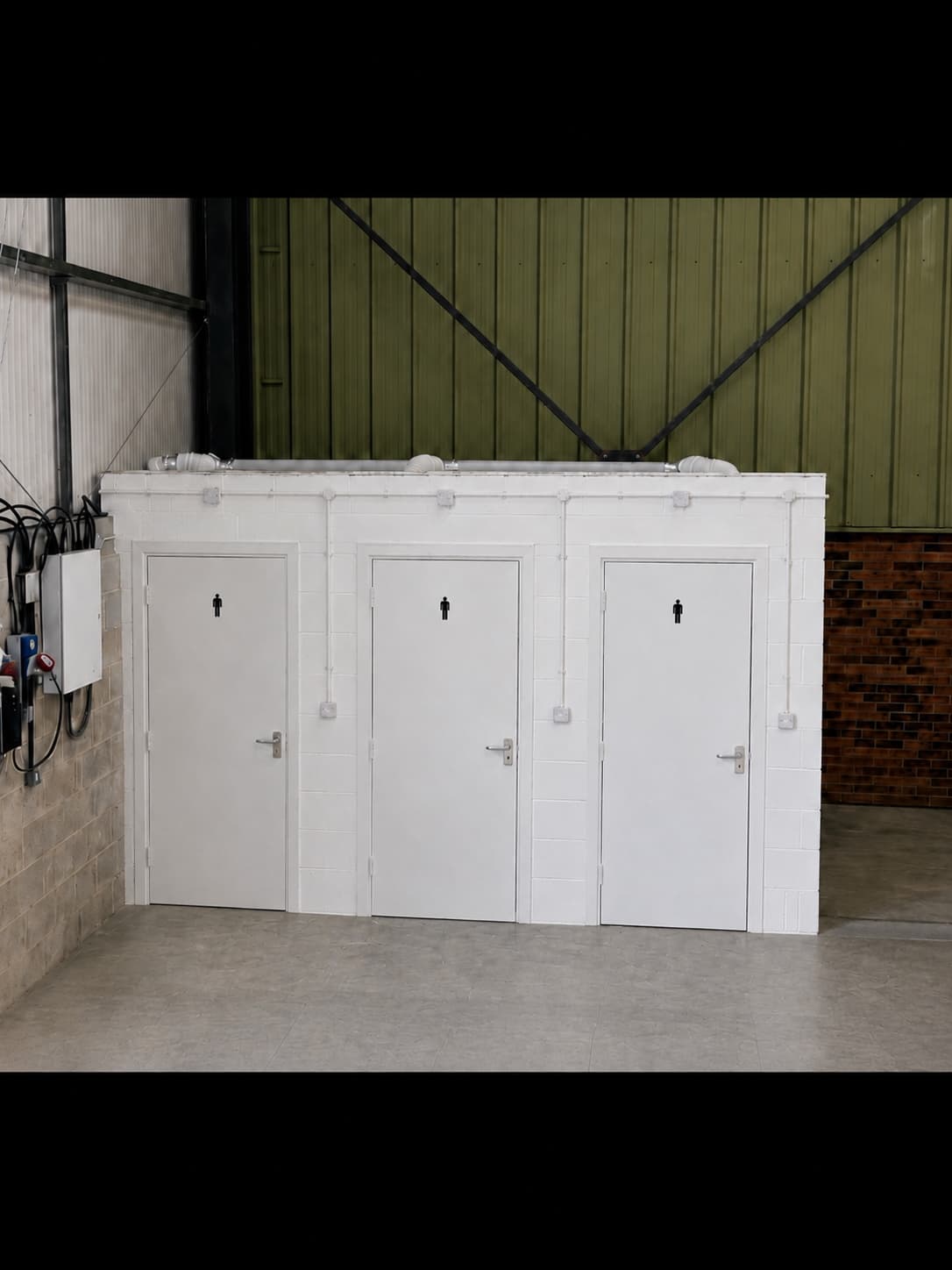 Three-cubicle staff toilet block built inside a commercial unit, finished in white block with new doors
