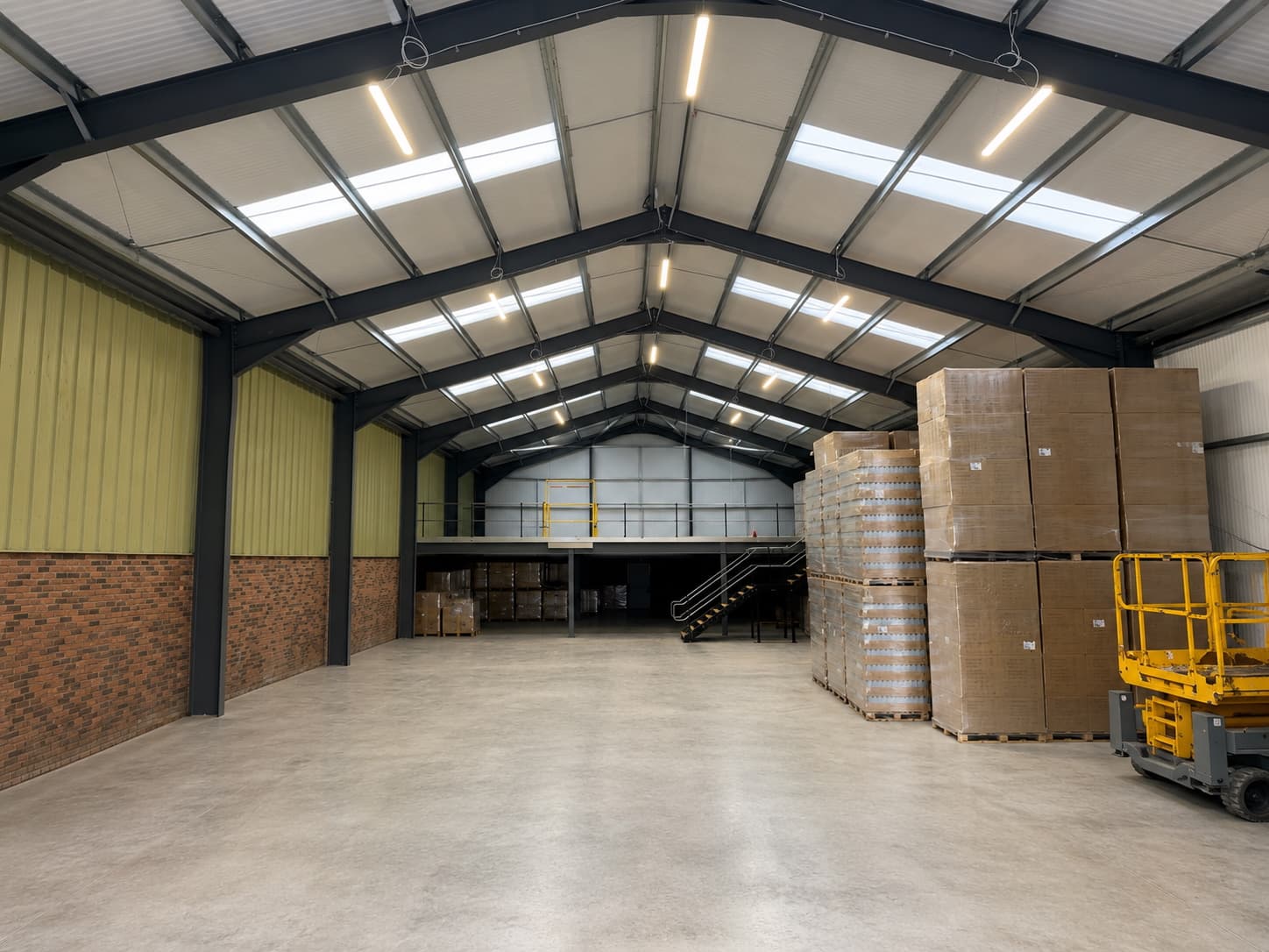 Finished commercial warehouse interior after Colver Construction fit-out — clean floor, mezzanine, lighting and palletised stock